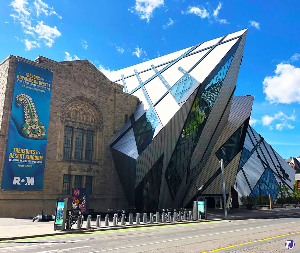 August 30, 2019 - The north facade of the East Wing (completed in 1933) and the Michael Lee-Chin Crystal (completed in 2007) at the ROM, looking southwest from Bloor St W and Queen's Park